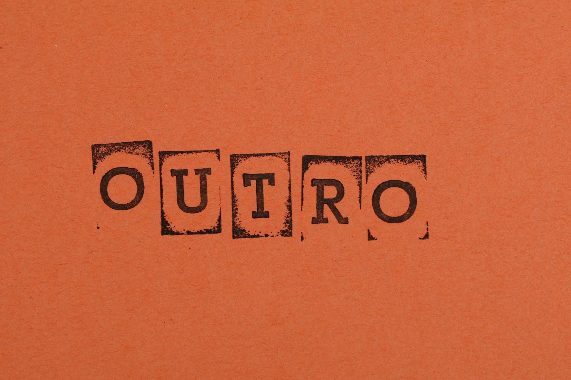 Close-up of the word OUTRO stamped on orange paper, highlighting typography and design.